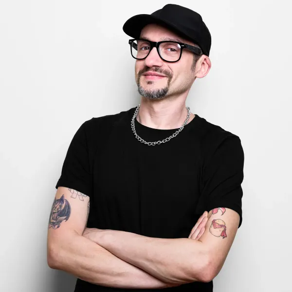 Antonio Mocci smiling in a black cap and glasses