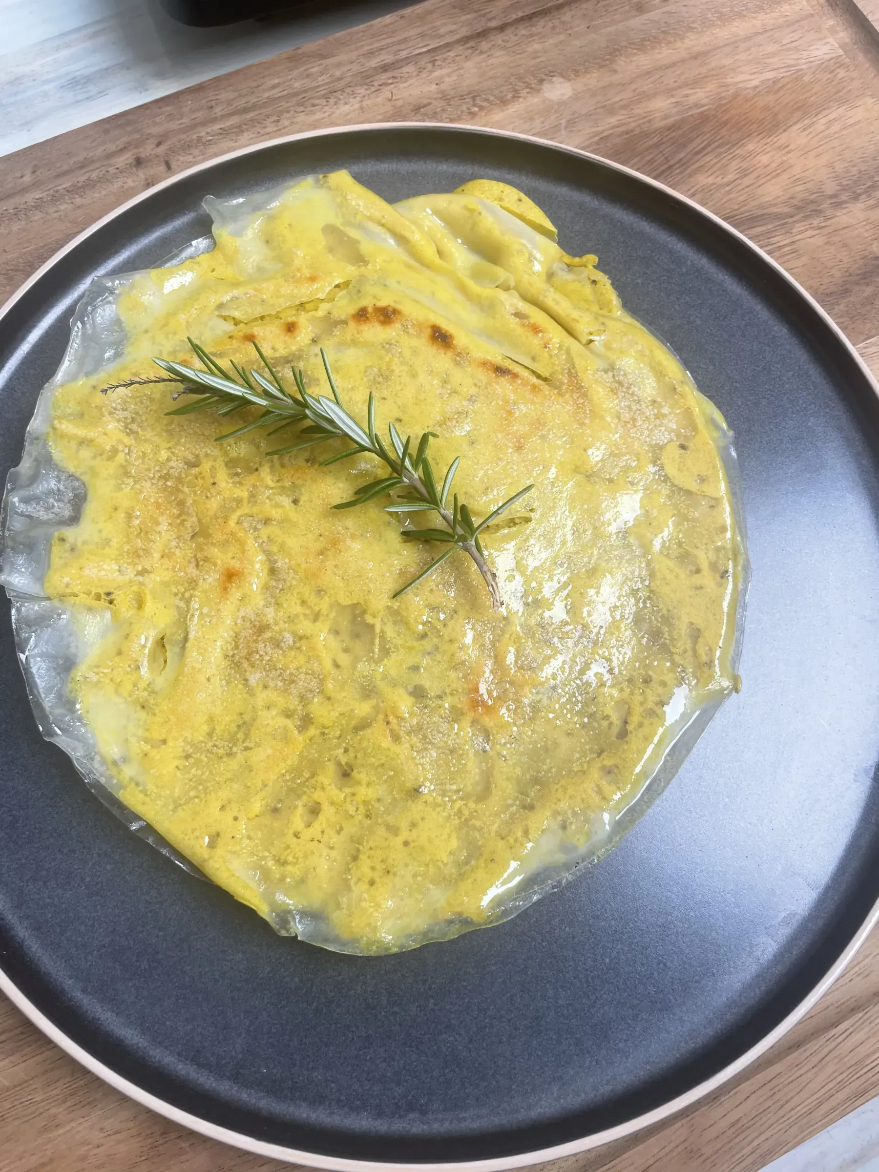 Golden vegan chickpea omelette encased in crisp rice paper on a plate with fresh rosemary