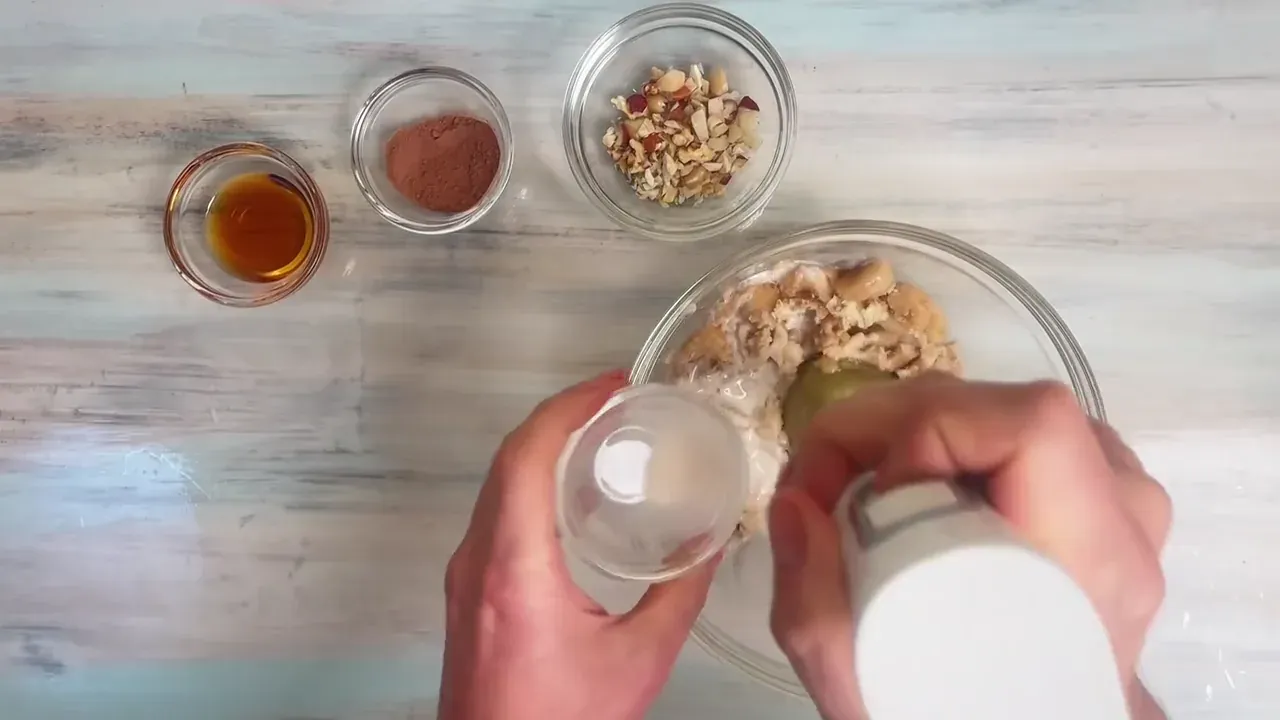 Add the cocoa powder, maple syrup, and half of the almond milk. Pulse several times to break up the frozen chunks.