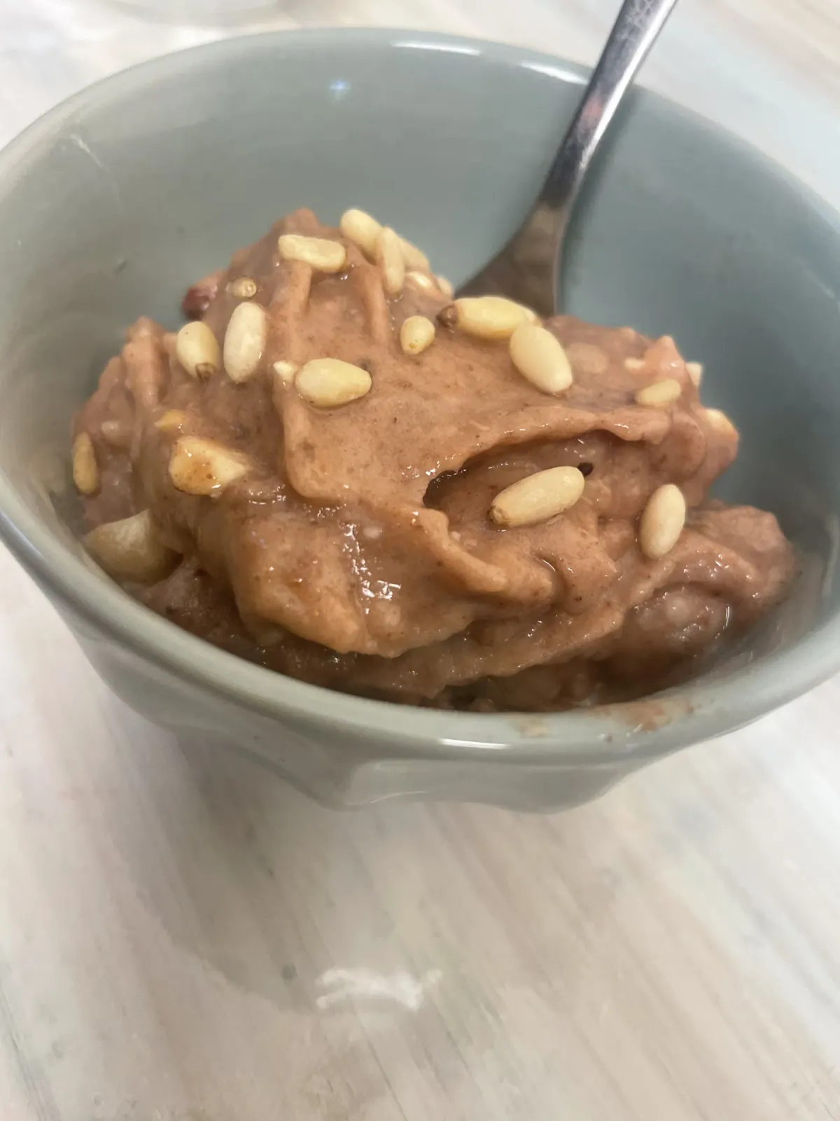 A ceramic bowl of creamy chocolate banana nice cream topped with toasted nuts