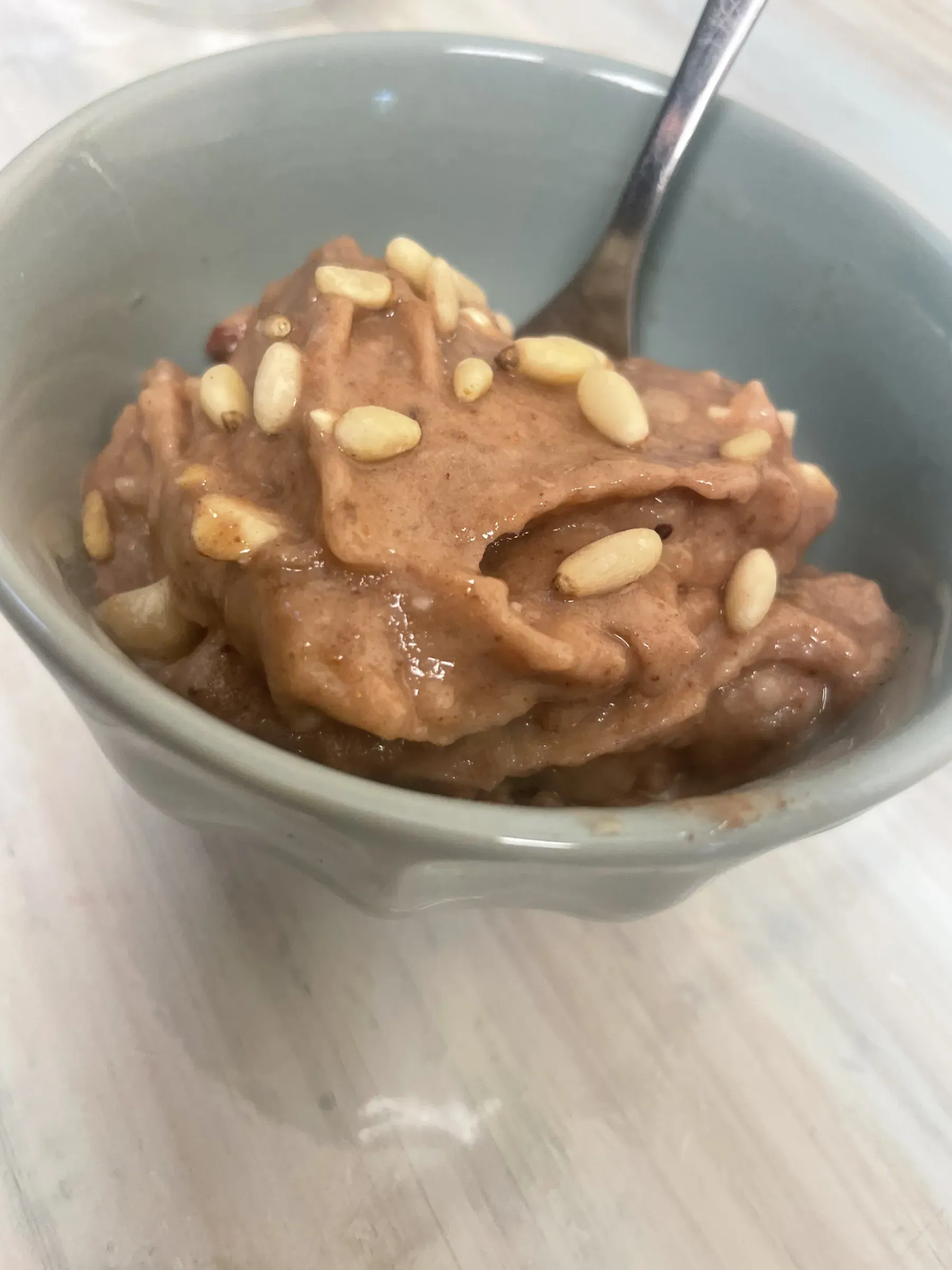 A ceramic bowl of creamy chocolate banana nice cream topped with toasted nuts