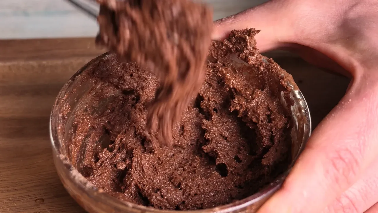 Thick chocolate batter lifted with a whisk in a glass bowl