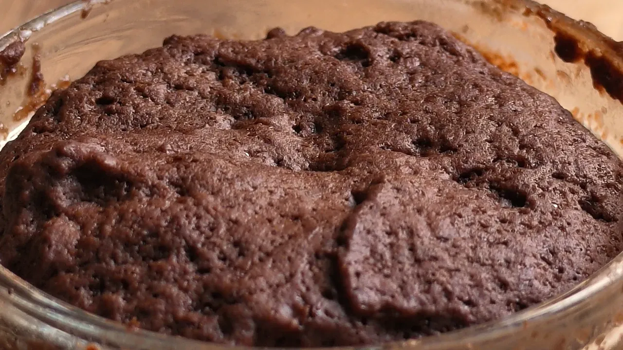 Close-up of the risen, cracked top of the microwave chocolate cake in its glass bowl