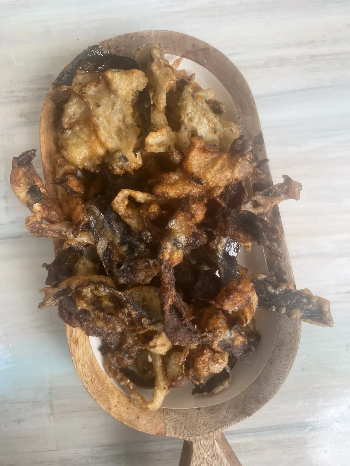 Golden crispy vegan anchovies made from tender marinated eggplant fillets on a wooden plate