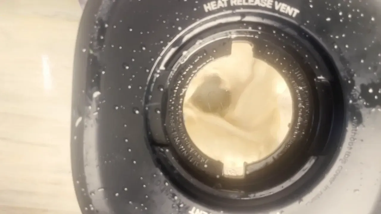 Smooth pale bean and plant milk mixture swirling inside a blender, seen from above through the lid