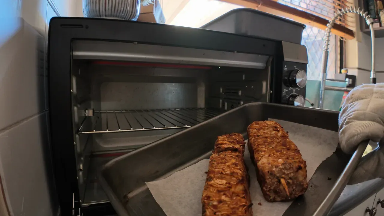 A baking tray with two golden-brown skewers pulled out of a small oven
