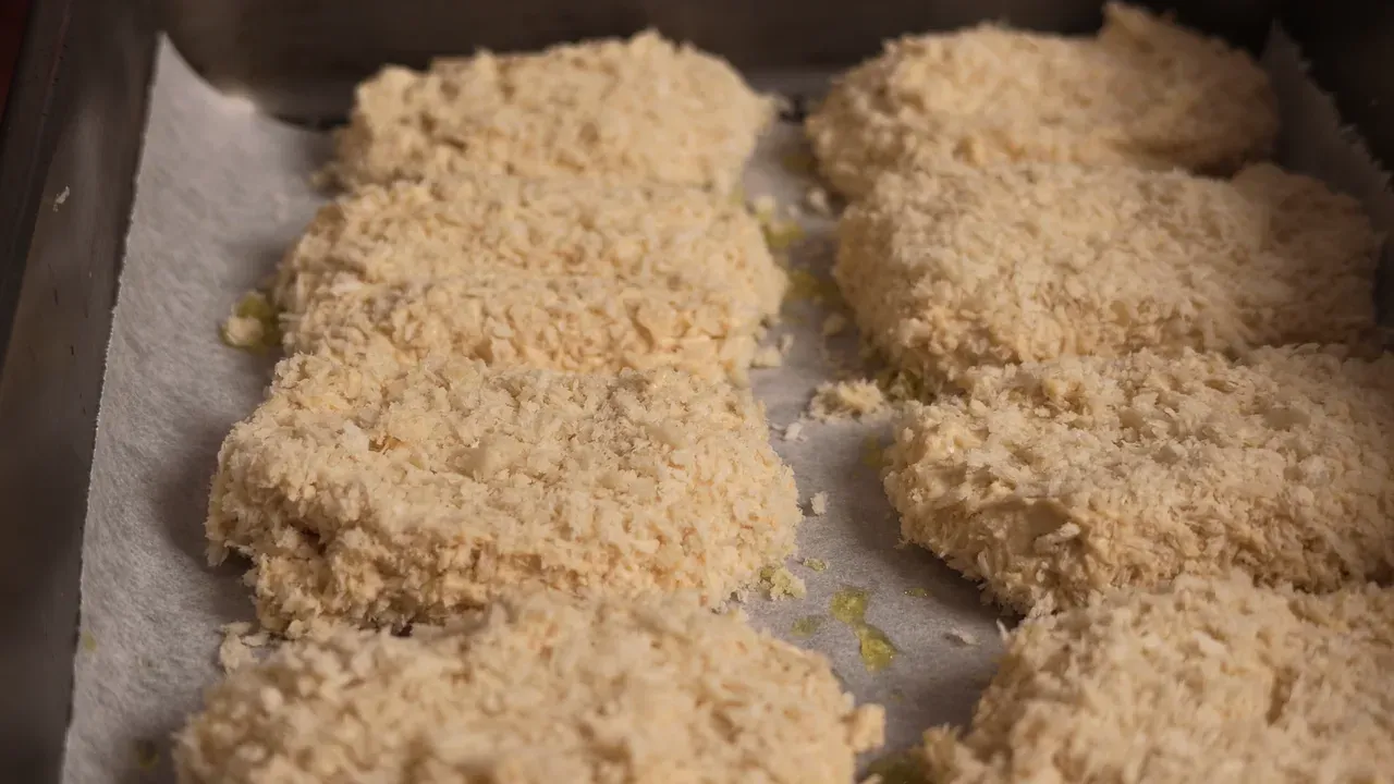 Raw nuggets coated in panko lined up on a baking tray lined with paper