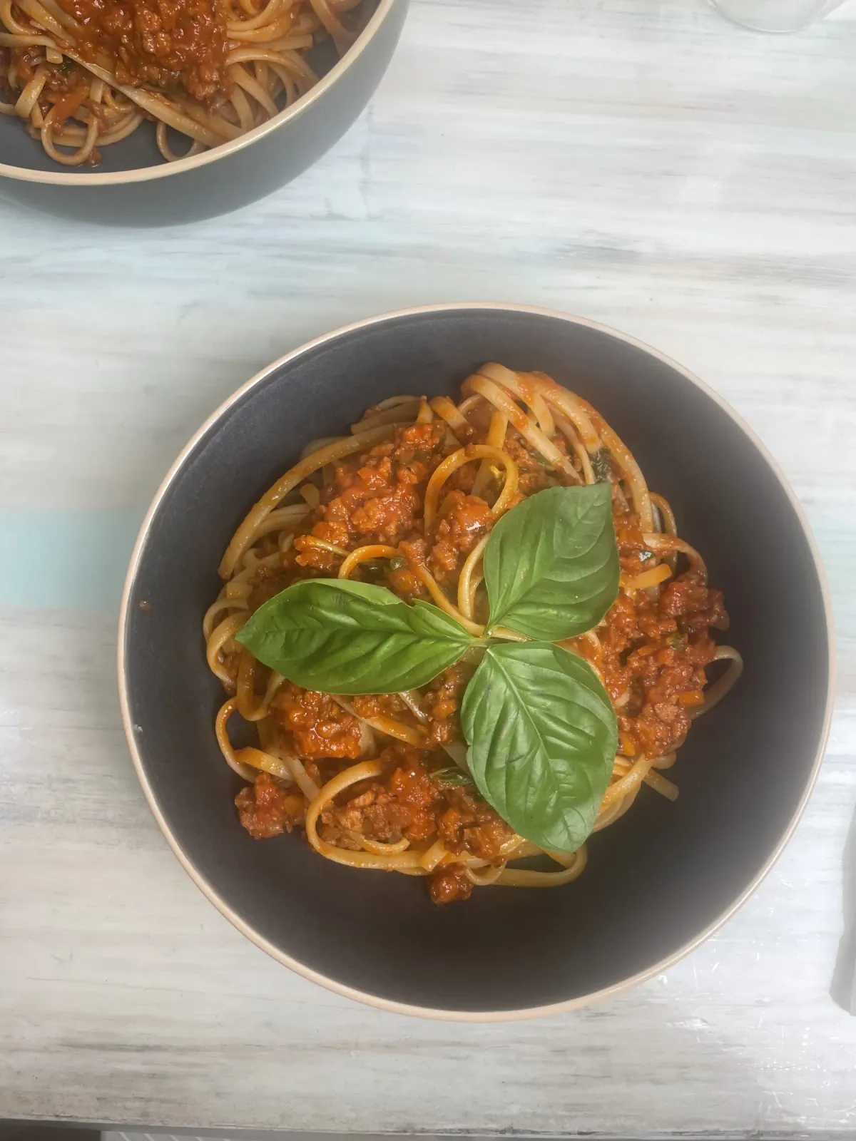 A bowl of tagliatelle pasta dressed in rich Italian vegan bolognese ragù topped with fresh basil