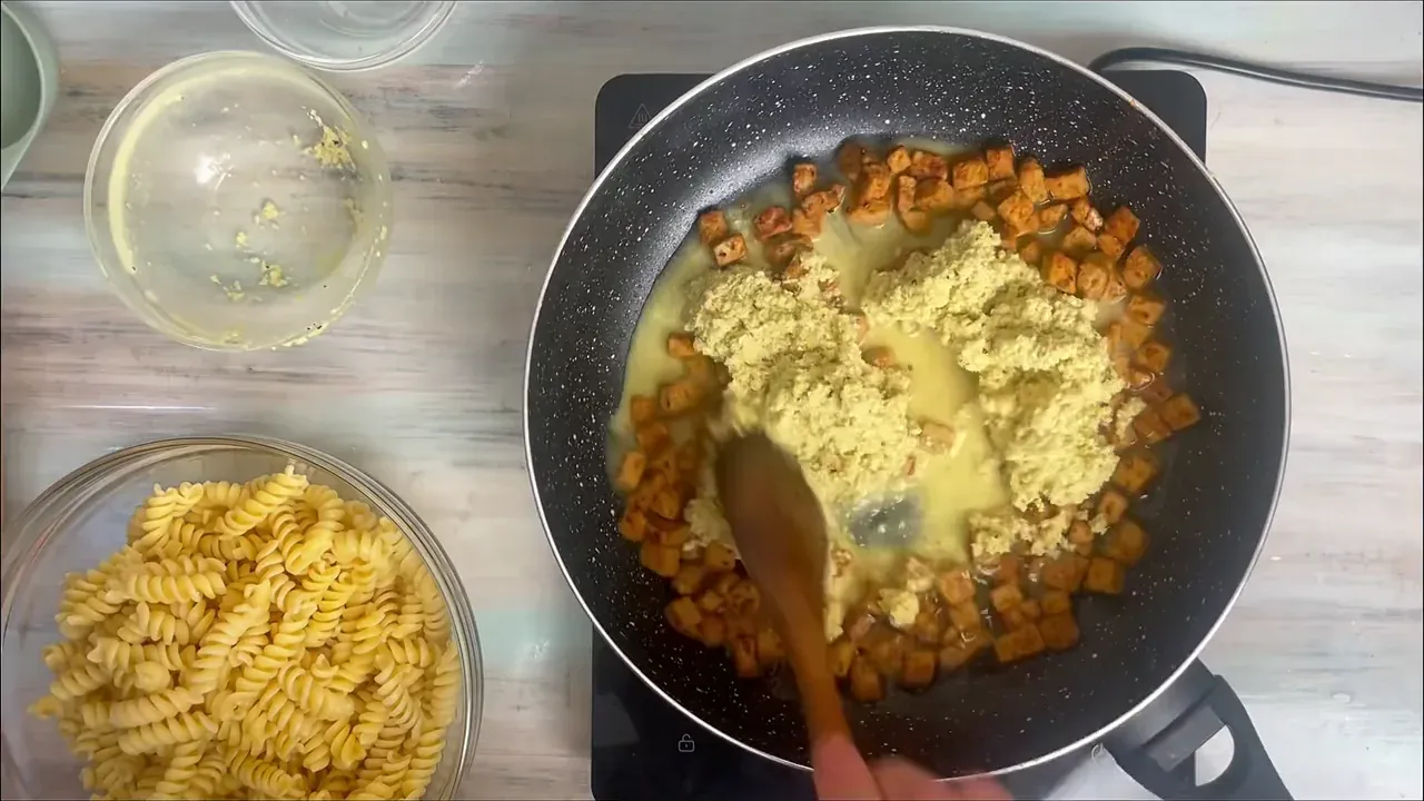 Verso la pasta scolata direttamente nella padella con il tempeh, unisco l'acqua di cottura tenuta da parte e aggiungo la crema di anacardi.