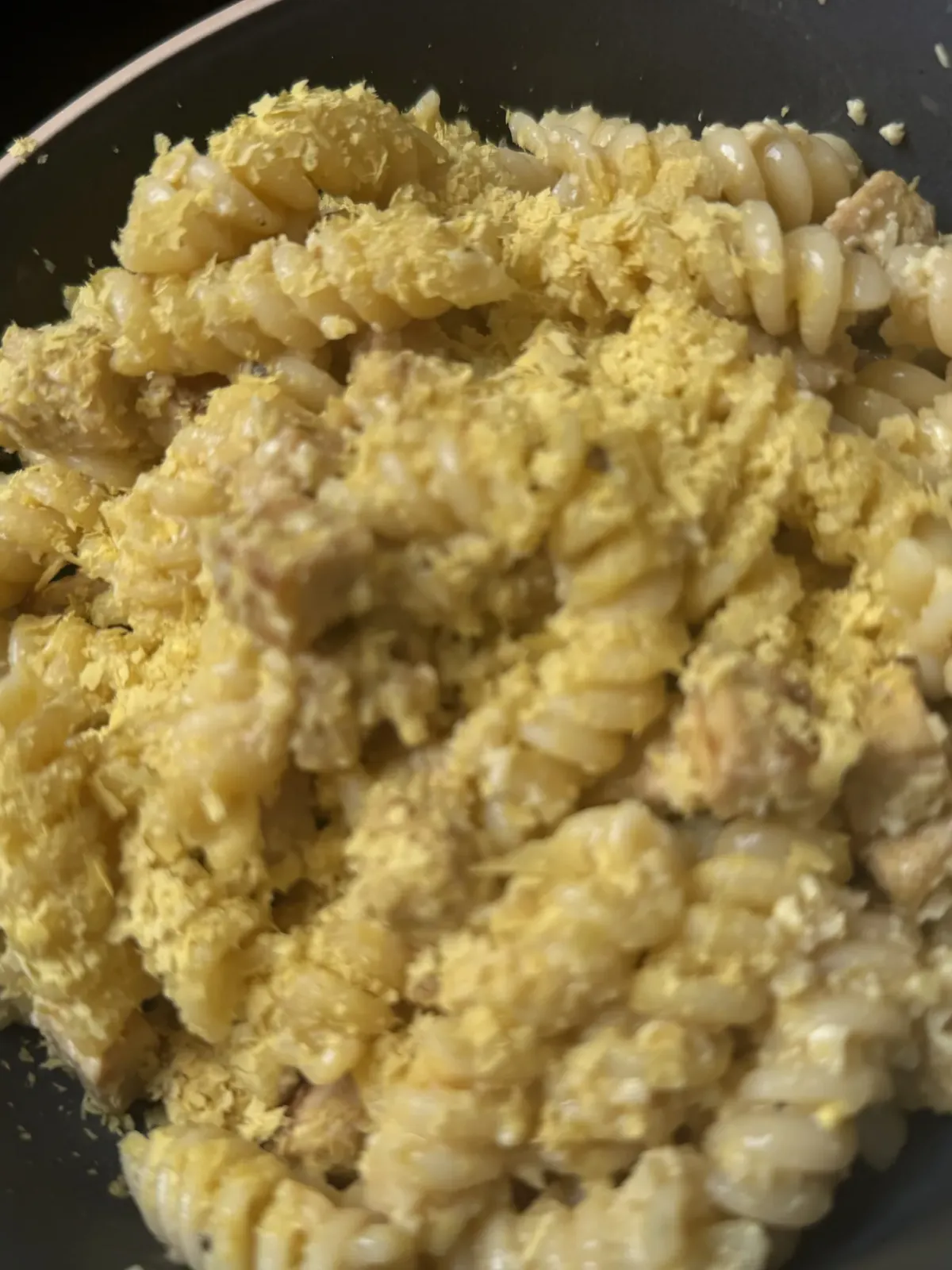 Un piatto fumante di carbonara vegana cremosa con salsa dorata agli anacardi, cubetti croccanti di tempeh rosolato e pepe nero fresco