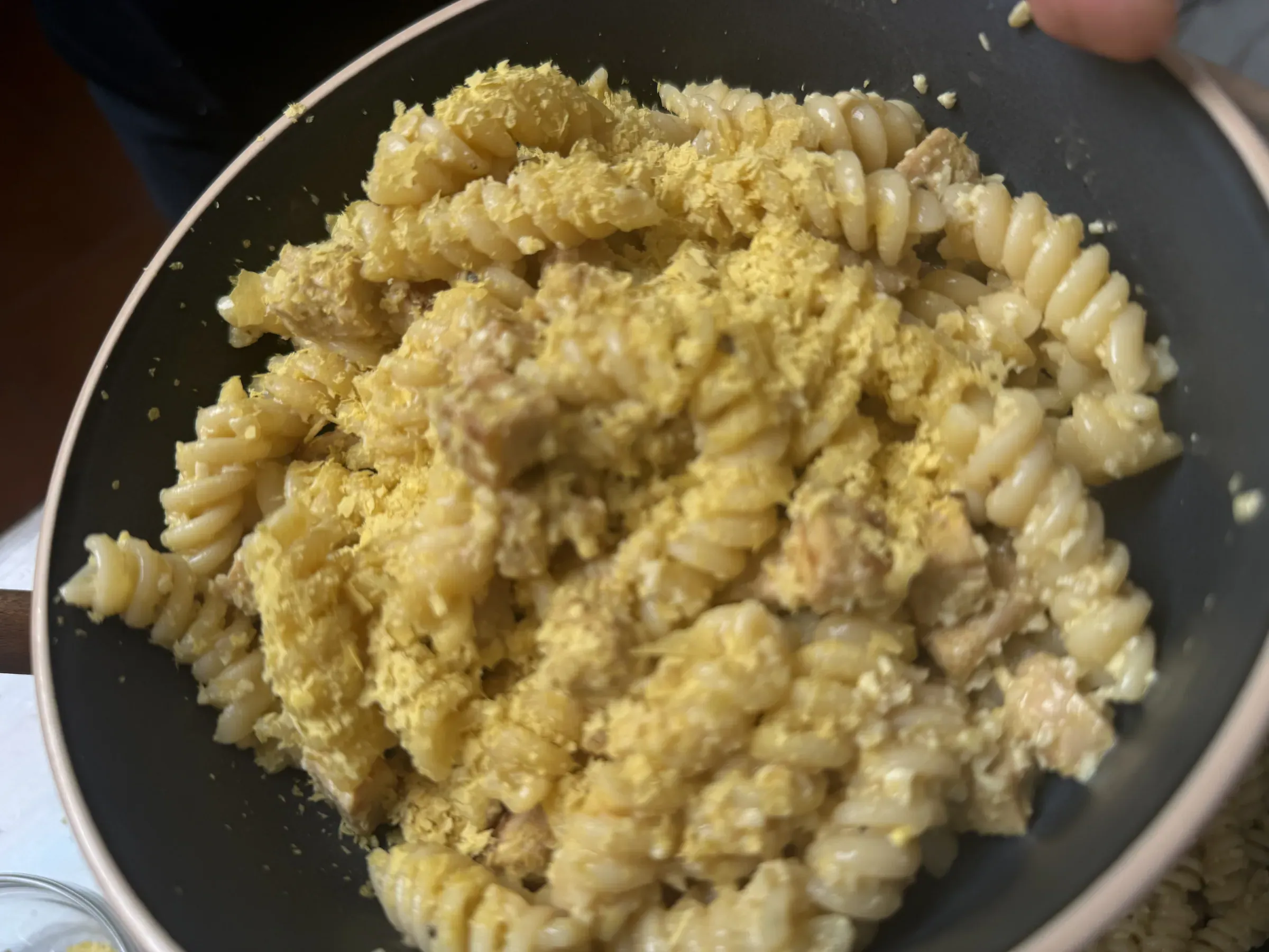 Un piatto fumante di carbonara vegana cremosa con salsa dorata agli anacardi, cubetti croccanti di tempeh rosolato e pepe nero fresco