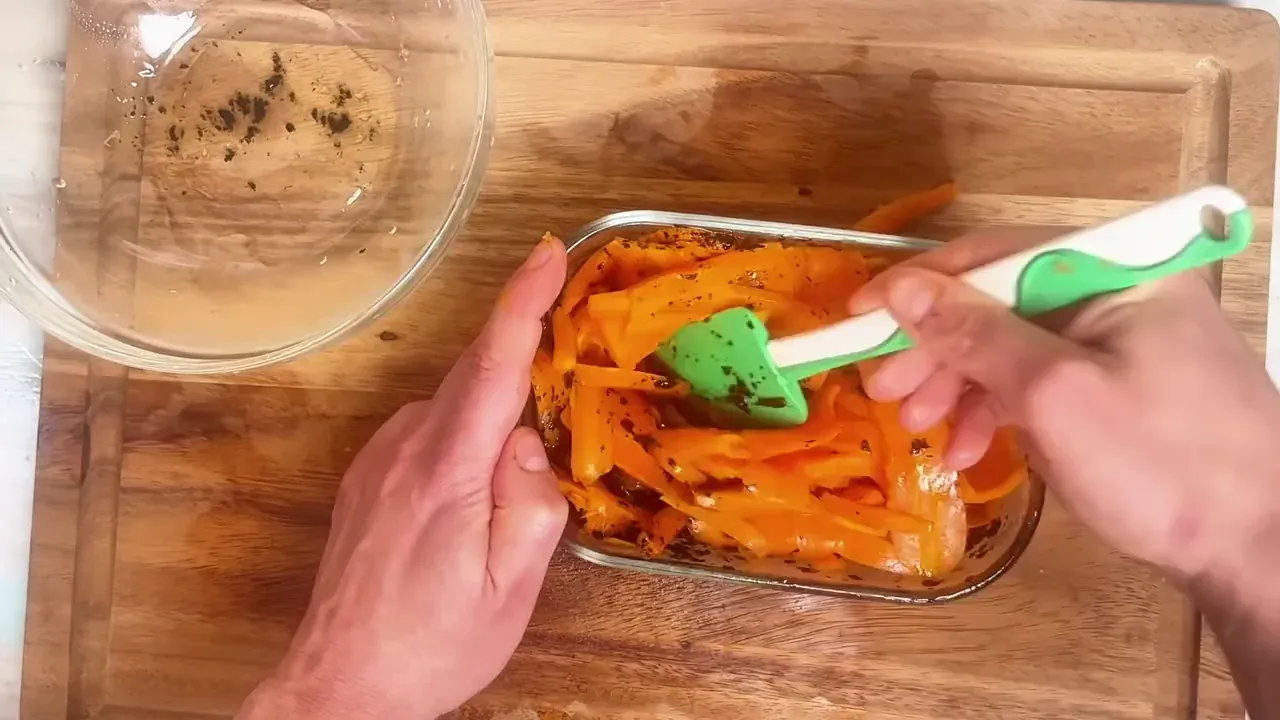 Place the carrot ribbons into the glass dish with the marinade. Use a spatula to gently fold and coat every ribbon thoroughly.