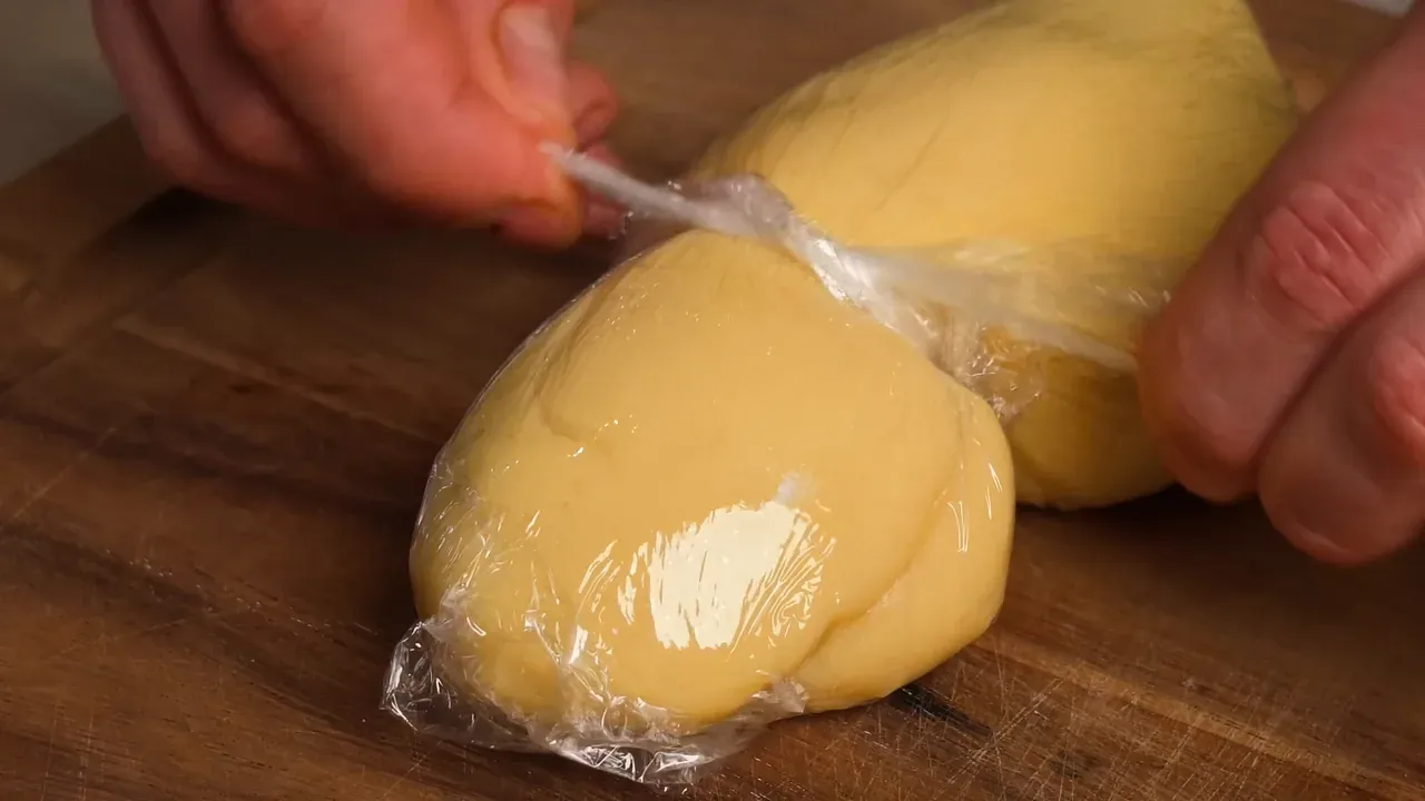 Dough wrapped in cling film, the film twisted to form the neck of a caciocavallo
