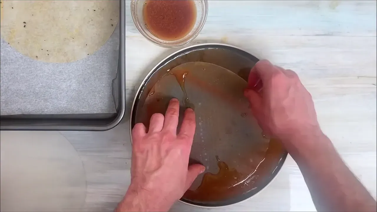 I dip a sheet of rice paper into the marinade for 2 to 3 seconds until pliable, lay it on parchment paper, then dip a second sheet and smooth it directly on top to create a sturdy two-layer sheet.