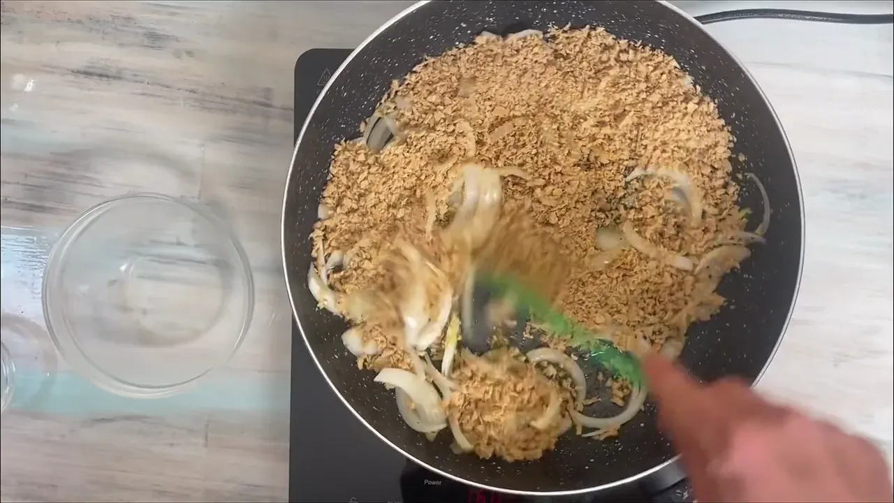Turn the heat up to medium, add the drained soy mince to the skillet, and sauté for 5 minutes, allowing the granules to lightly brown and absorb the onion oil.