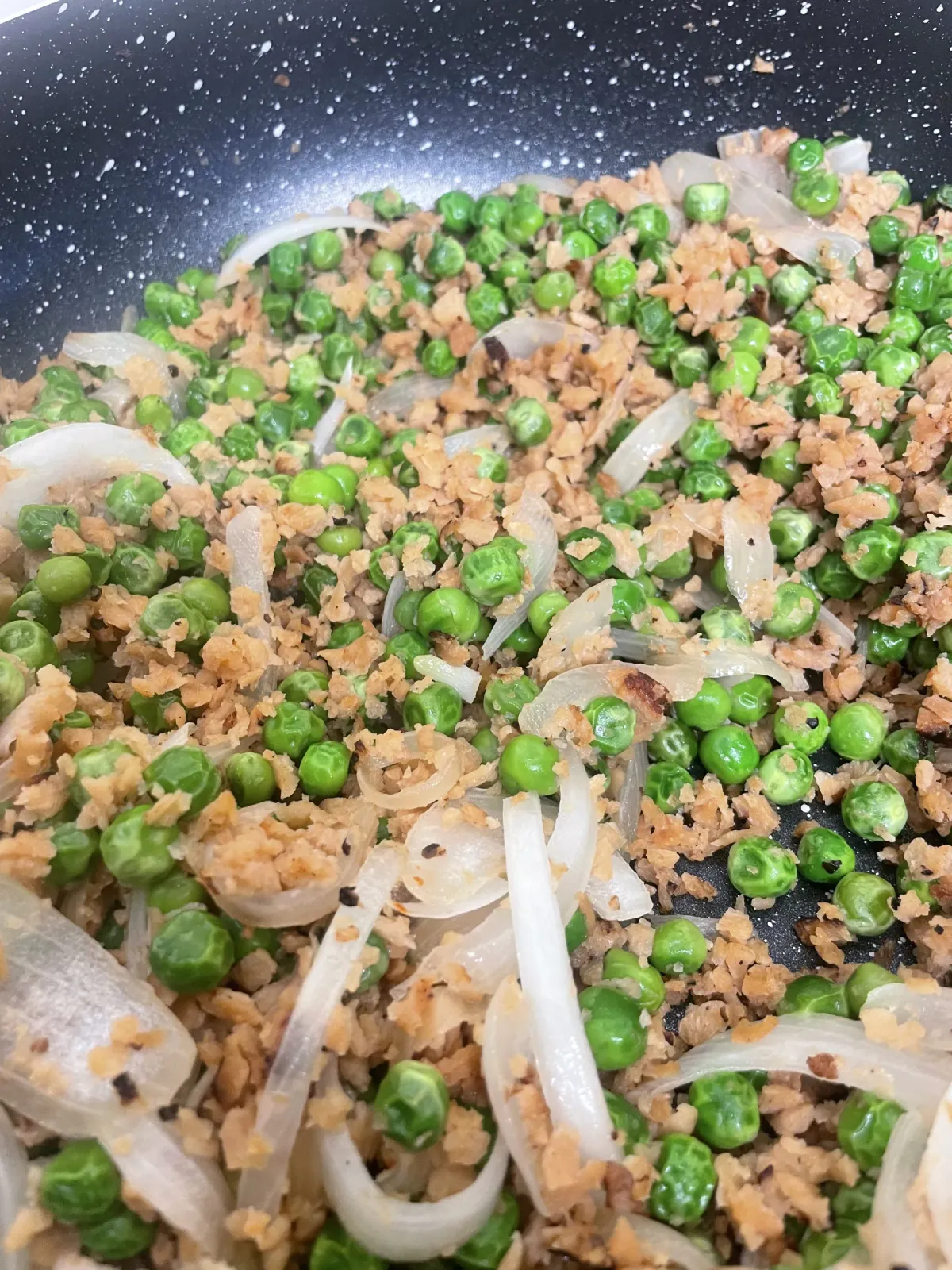 A skillet of seasoned vegan soy mince tossed with bright green peas and caramelized onions