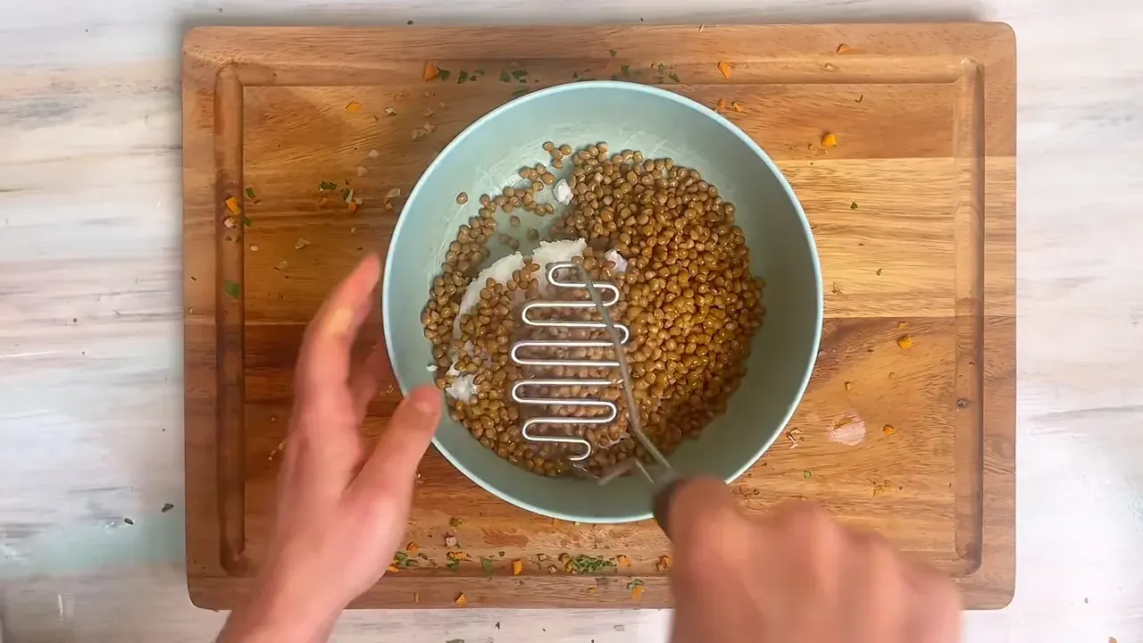 In a large mixing bowl, combine the overcooked white rice and cooked brown lentils. Mash thoroughly with a potato masher until partially broken down and sticky.