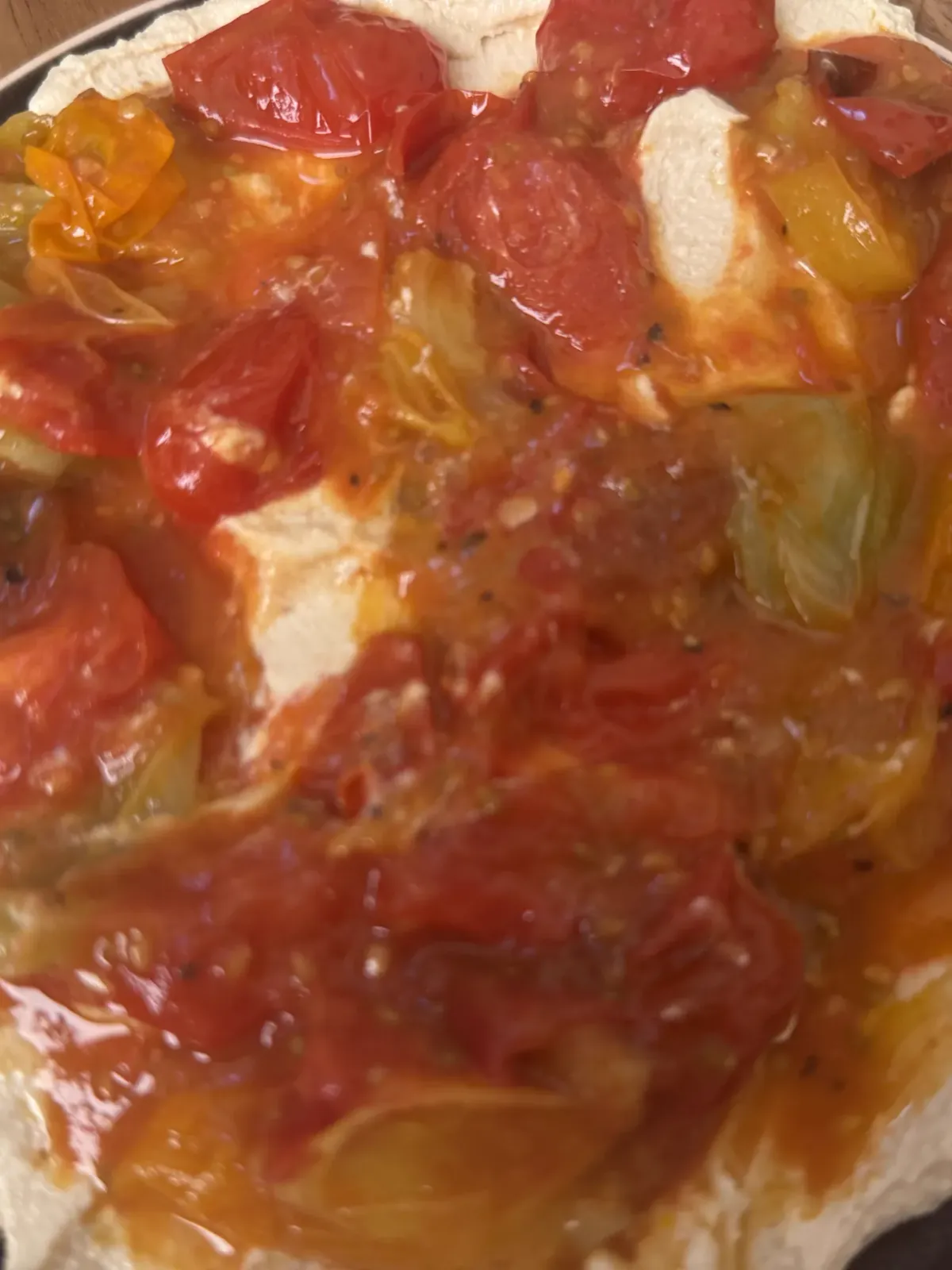 A plate of velvety whipped tofu cream topped with warm blistered cherry tomato confit, rich pan juices, and fresh basil