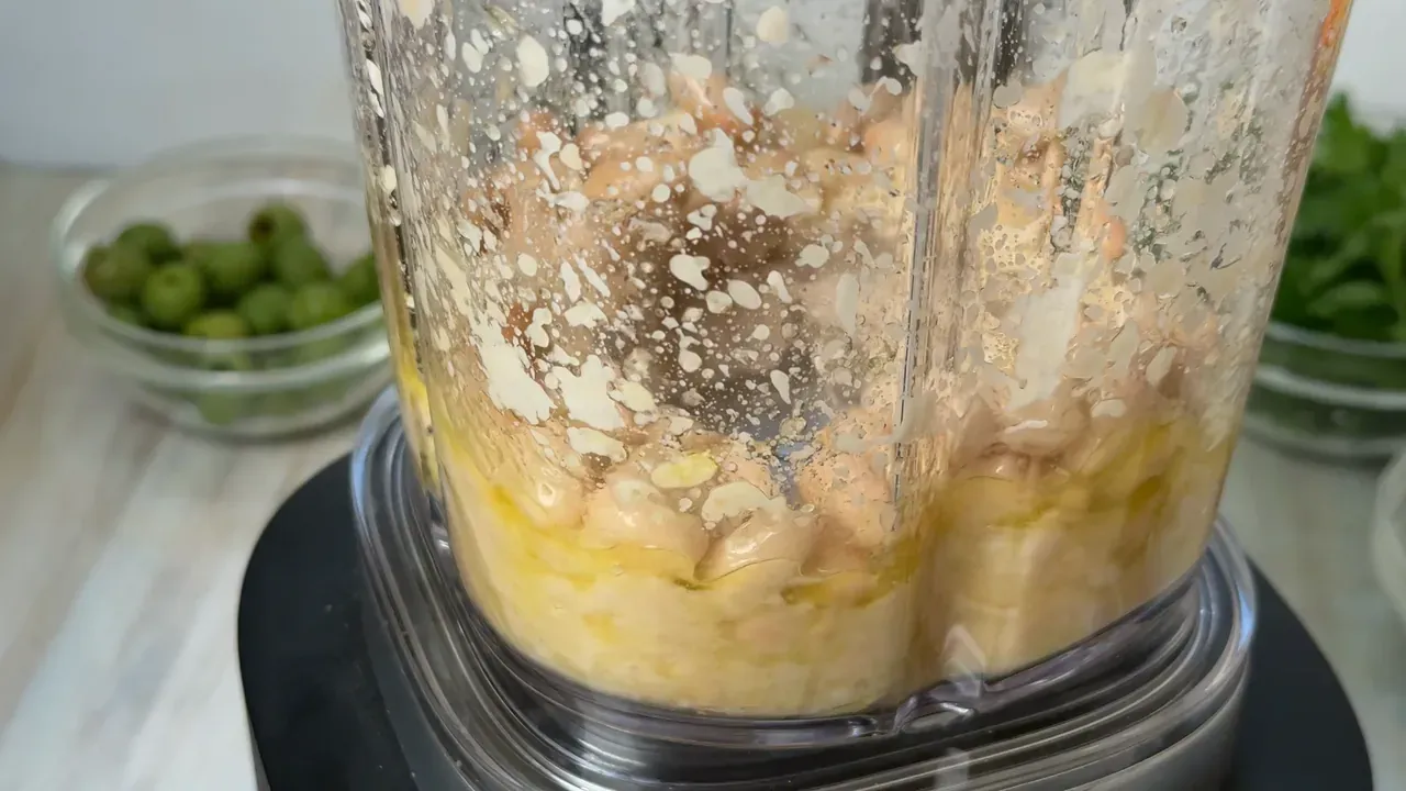 Drained white beans and olive oil in a blender jug, starting to break down into a cream